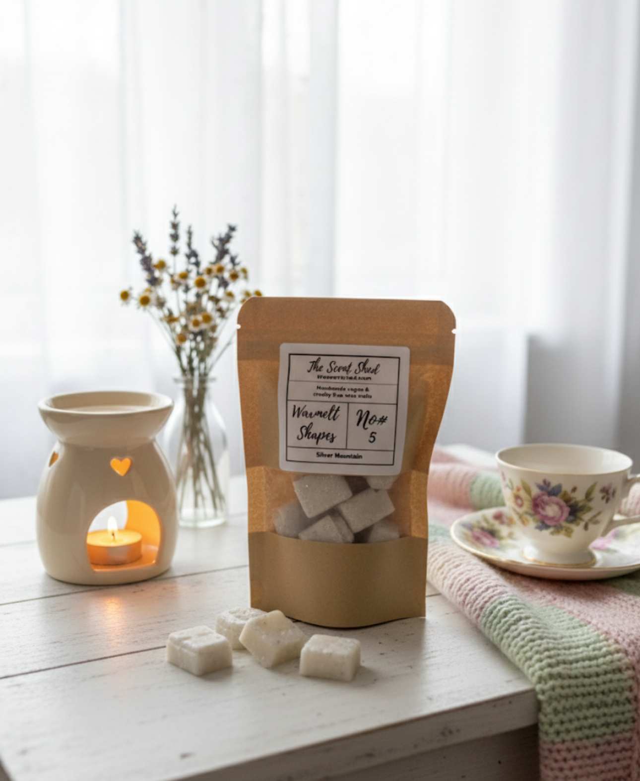 Packaged product with a candle and tea cup on a wooden surface